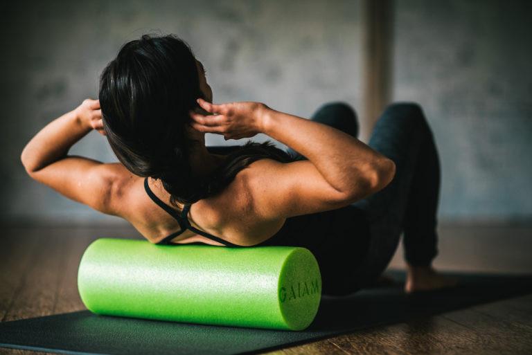 a woman exercises with a green foam roller